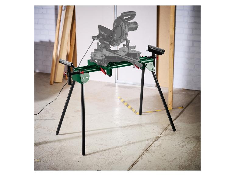 Support vert pour scie à onglet avec pieds noirs et scie à onglet grise en arrière-plan d'atelier.