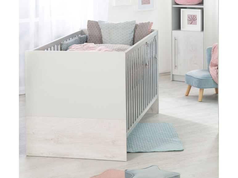 Un lit bébé avec des détails en bois et un tapis bleu clair.
