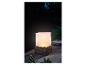 Une lampe blanche dans un panier en rotin noir, sur une table en bois.
