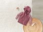 Un pull rose à capuche pour bébé et deux jouets en bois en forme de champignons.