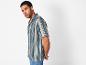 Modèle masculin portant une chemise à rayures bleu marine et beige.