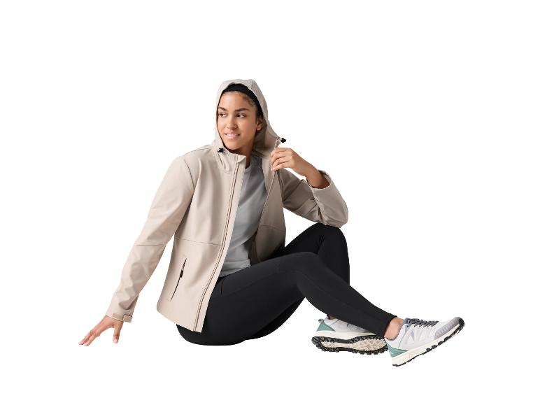 Femme en veste beige à capuche, leggings noirs et baskets, assise.