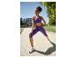 Femme en brassière de sport violette et legging capri s'étirant à l'extérieur.