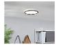 Plafonnier rond moderne au design minimaliste, installé dans une pièce avec une plante et une étagère.