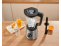 Mixeur avec glaçons, jus d'orange et tranches d'orange sur un comptoir en bois.