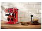 Machine à expresso rouge avec deux verres de café, un bol de biscuits et des grains de café.