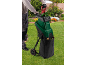 Une personne utilise un broyeur de jardin Parkside pour hacher des feuilles dans un sac de collecte.