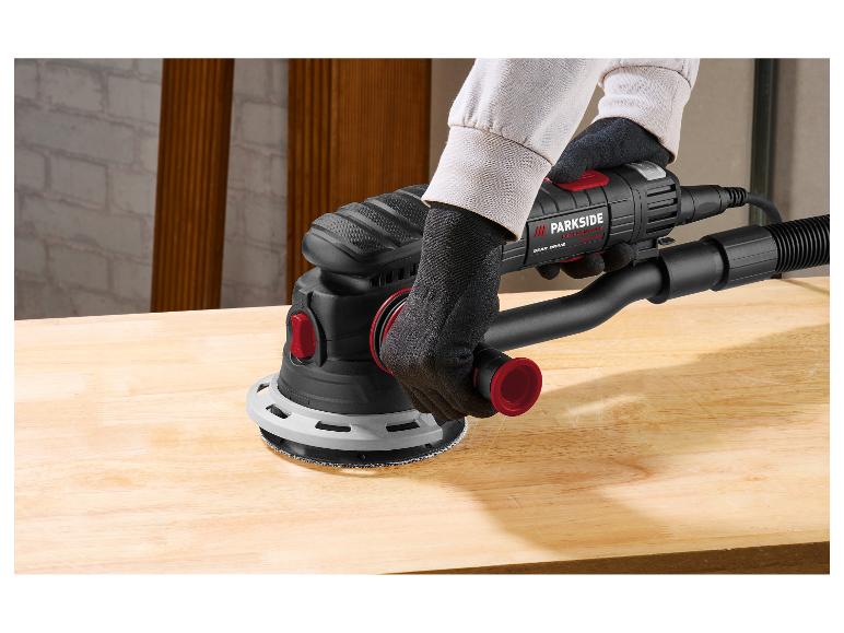 Ponceuse excentrique en action sur un établi en bois.