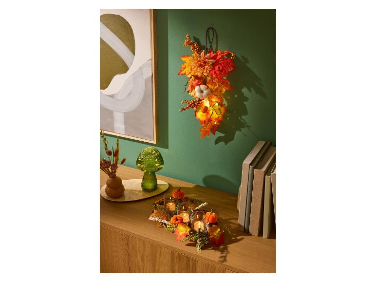 Décoration d'automne LIVARNO home avec lumières LED, bougies et feuilles colorées.
