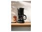 Cafetière filtre noire avec café fraîchement moulu dans une cuisine moderne.