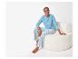 Femme en pyjama bleu à motifs floraux assise sur un pouf blanc.