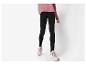 Femme en pull rose et leggings noirs avec des baskets beiges