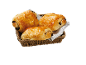 Trois pains au chocolat dorés dans un panier tressé avec une serviette blanche et noire.