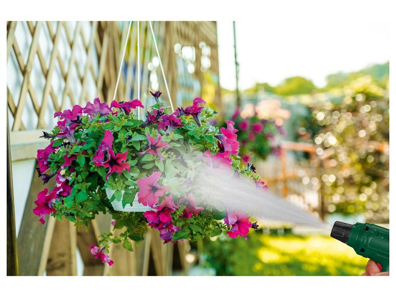 Arrosage de pétunias suspendus dans un pot avec un pistolet d'arrosage vert.