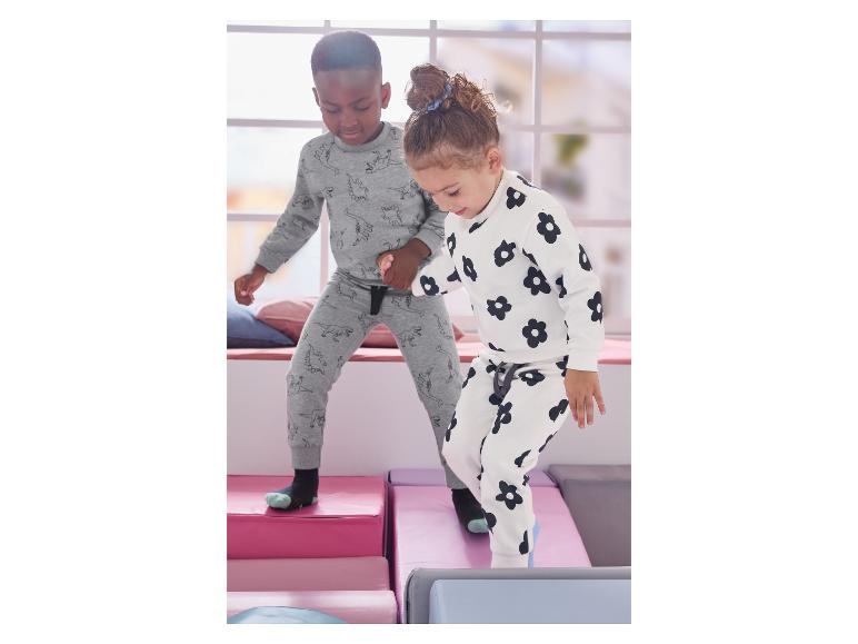 Deux enfants en pyjama dinosaure et fleuri, jouant sur des blocs souples.