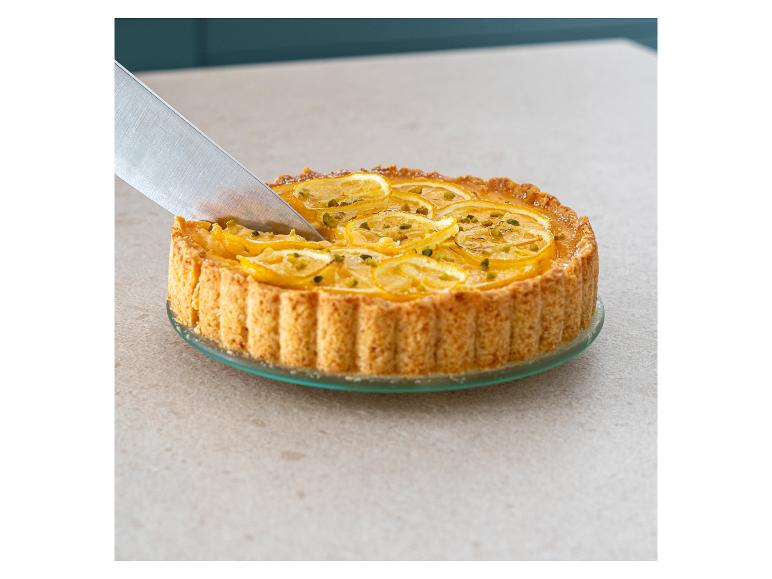 Une tarte au citron et à la pistache que l'on coupe avec un couteau