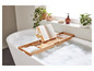 Un bain moussant avec un plateau en bambou contenant un verre de vin, un livre et un téléphone.