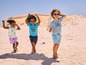 Des enfants en vêtements d'été jouant sur la plage.