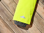 Combinaison de ski jaune avec un logo montagne réfléchissant sur un fond en bois.