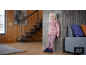 Fillette en pull en tricot rose, leggings et bottes d'hiver contre un mur en bois.