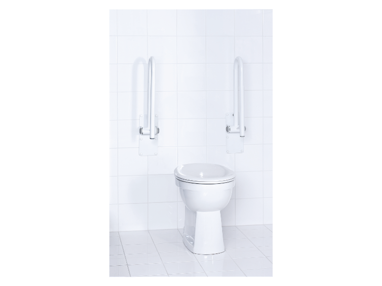 WC blanc avec accessoires pour personnes âgées sur fond de carrelage blanc.