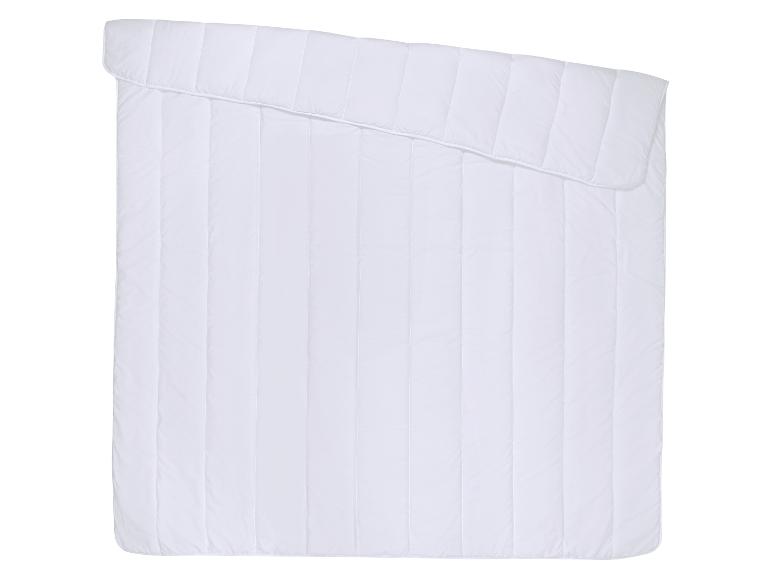 Couette blanche matelassée avec surpiqûres verticales et bord supérieur replié.