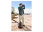 Homme en chaussures de trekking CRIVIT regardant avec des jumelles sur une plage de sable.