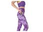 Femme en legging et brassière de sport violets, mettant un téléphone dans la poche latérale.