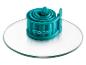 Un anneau de cuisson en silicone turquoise de la marque Coox sur un dessous de plat en verre.