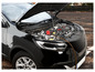 Une voiture noire avec le capot ouvert, montrant le moteur et un produit LUKAS.