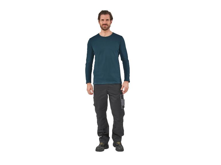 Homme portant un t-shirt à manches longues bleu foncé et un pantalon de travail gris.