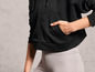 Un sweat-shirt à capuche noir à fermeture éclair et un legging gris.