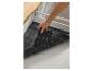 Main d'homme plaçant un tapis de tiroir gris foncé avec des marques de coupe dans un tiroir de cuisine.