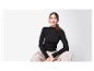 Femme en pull noir et pantalon beige.