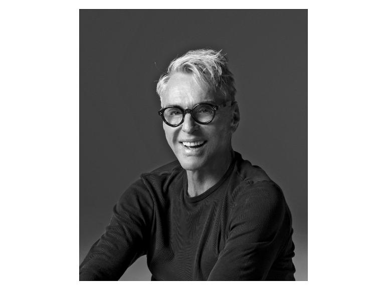 Homme souriant avec des lunettes, cheveux gris, en chemise noire.