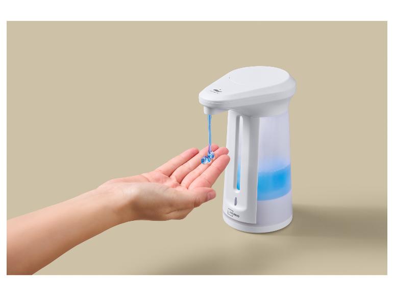 Une main reçoit du savon d'un distributeur automatique avec du liquide bleu.