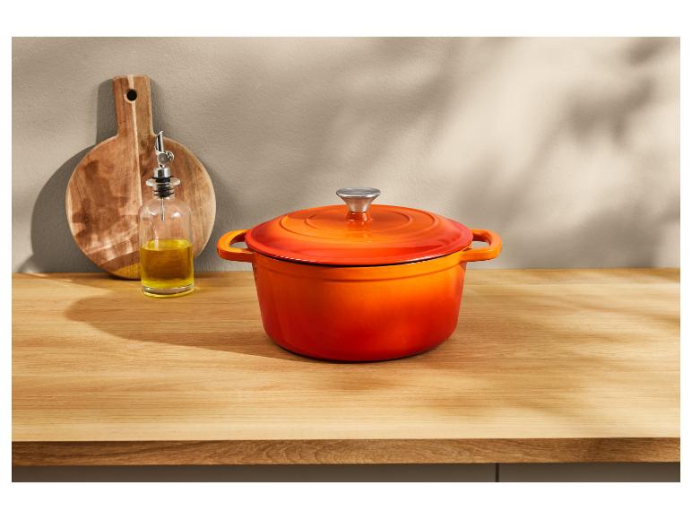 Cocotte Le Creuset orange sur un plan de travail en bois.