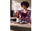 Une femme prépare un smoothie dans la cuisine à l'aide d'un blender.