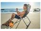 Homme se relaxant sur une chaise de plage avec une bouteille d'eau et une serviette.