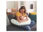 Une mère allaite son bébé assis sur un canapé avec un coussin d'allaitement.