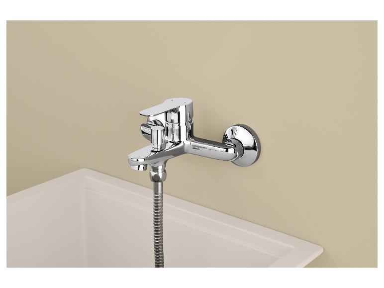 Mitigeur de douche mural chromé avec flexible, au-dessus d'un receveur de douche blanc.