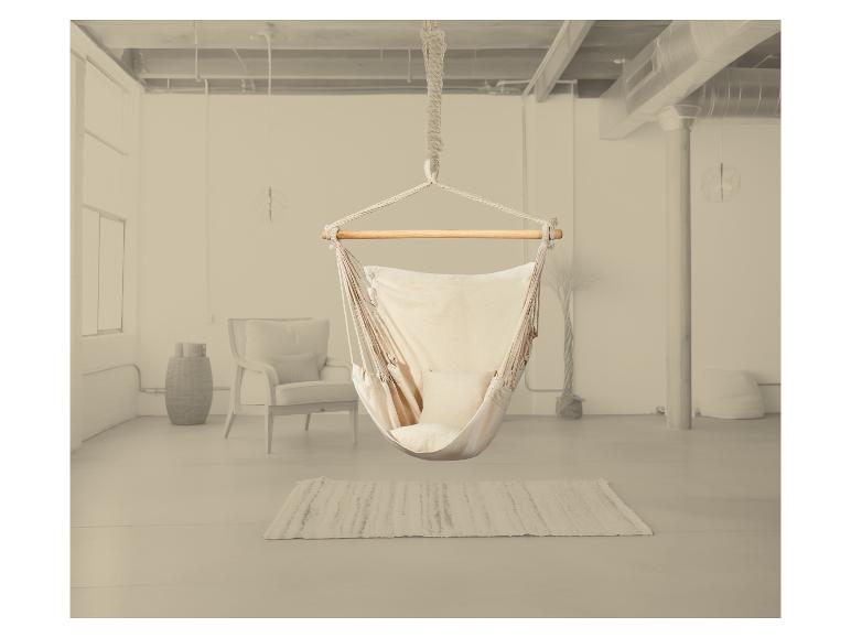 Chaise hamac suspendue dans un intérieur lumineux avec tapis et fauteuil.