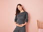 Une femme enceinte porte un sweat-shirt et un pantalon de survêtement gris foncé et confortables.