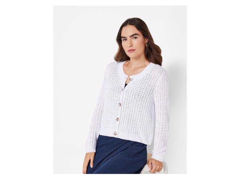 Une femme porte un cardigan blanc en tricot avec des boutons.