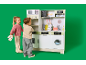 Des enfants jouent avec une cuisine en bois pour enfants sur fond vert.