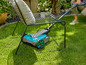 Un robot tondeuse bleu à côté d'une chaise dans un jardin.