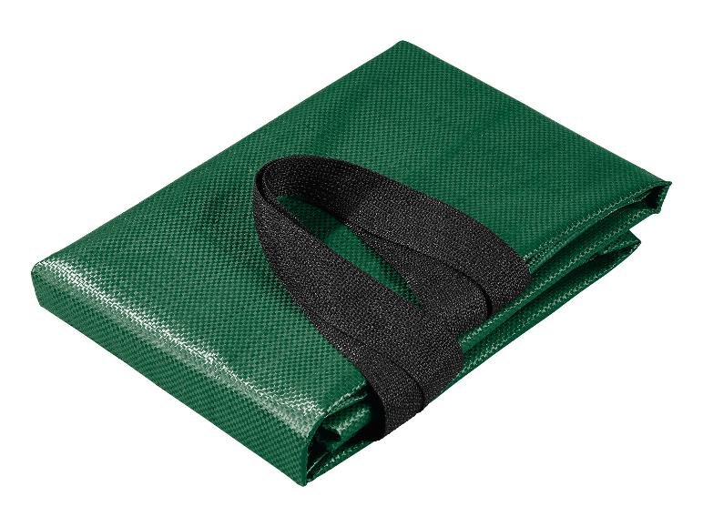 Une bâche verte pliée avec une sangle noire sur fond blanc.