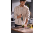 Homme dans la cuisine préparant du pesto avec un mixeur plongeant.