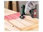 Outil multifonction sans fil ponçant une surface en bois peinte en rouge.