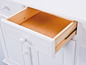 Un tiroir ouvert d'une commode blanche avec un intérieur en bois.